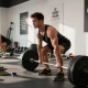 Anabolika Shop Deutschland: Bodybuilder beim intensiven Training im Fitnessstudio mit Gewichten und motivierenden Zitaten im Hintergrund.